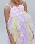 Pastel-colored dress with ruffles worn by a child, blurred green background