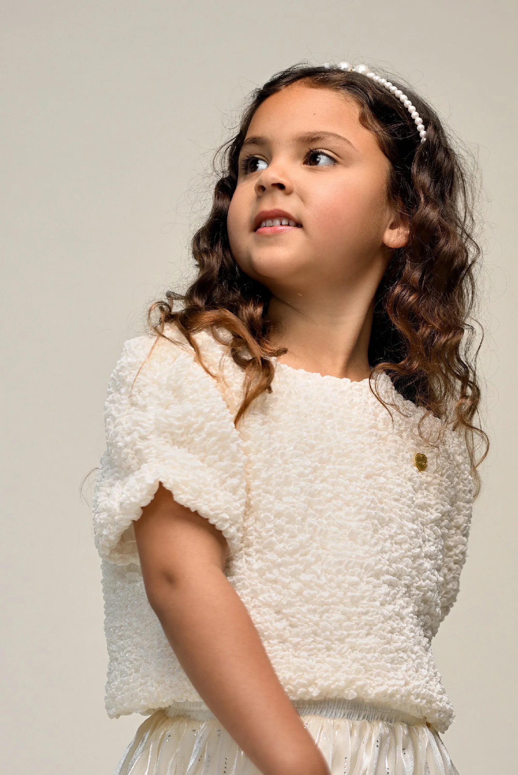 Young girl wearing a white textured top and skirt  by Le Chic