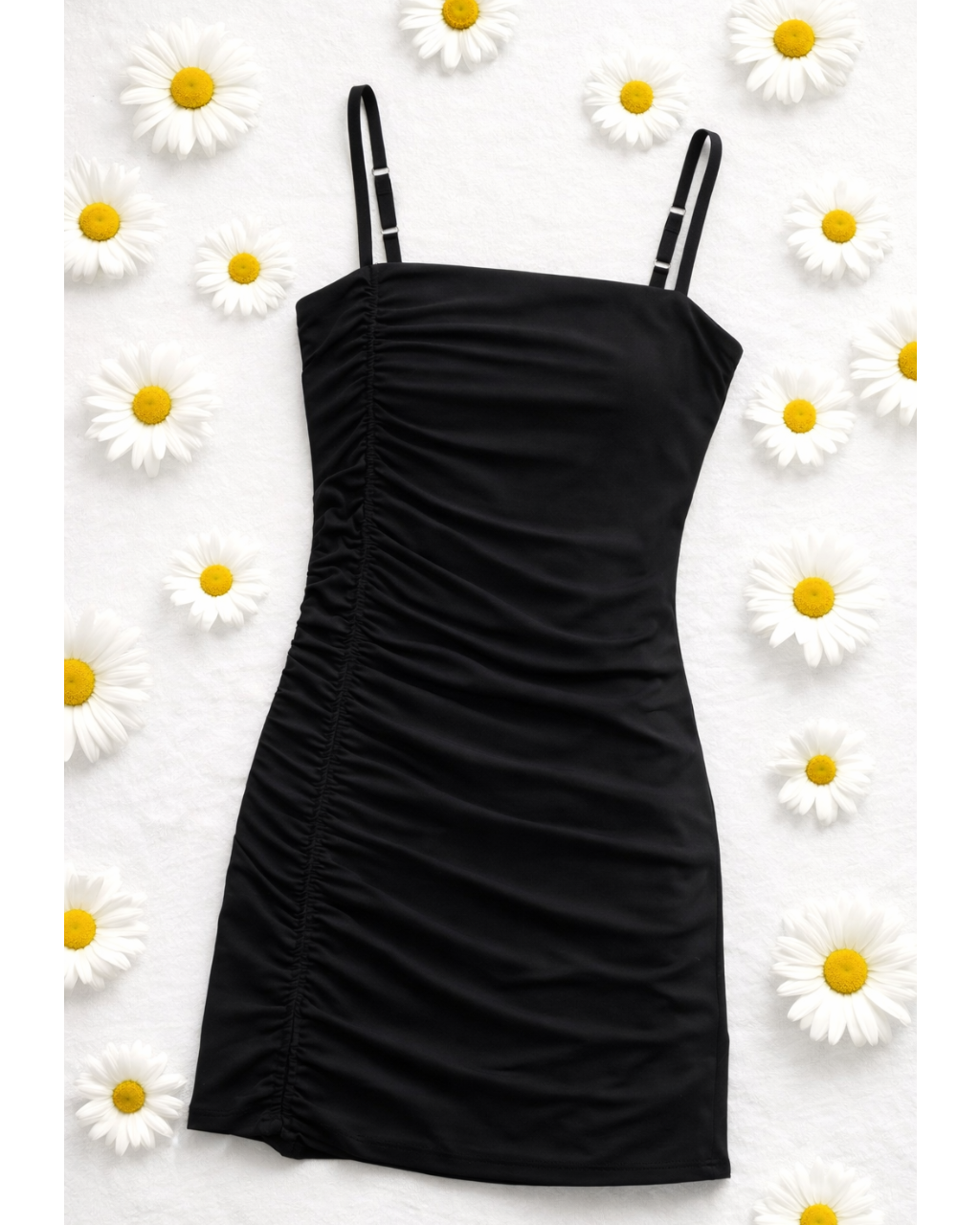Black dress with thin straps on a white background with daisies