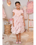 Young girl in a pink ruffled dress standing in a room with pink decor.