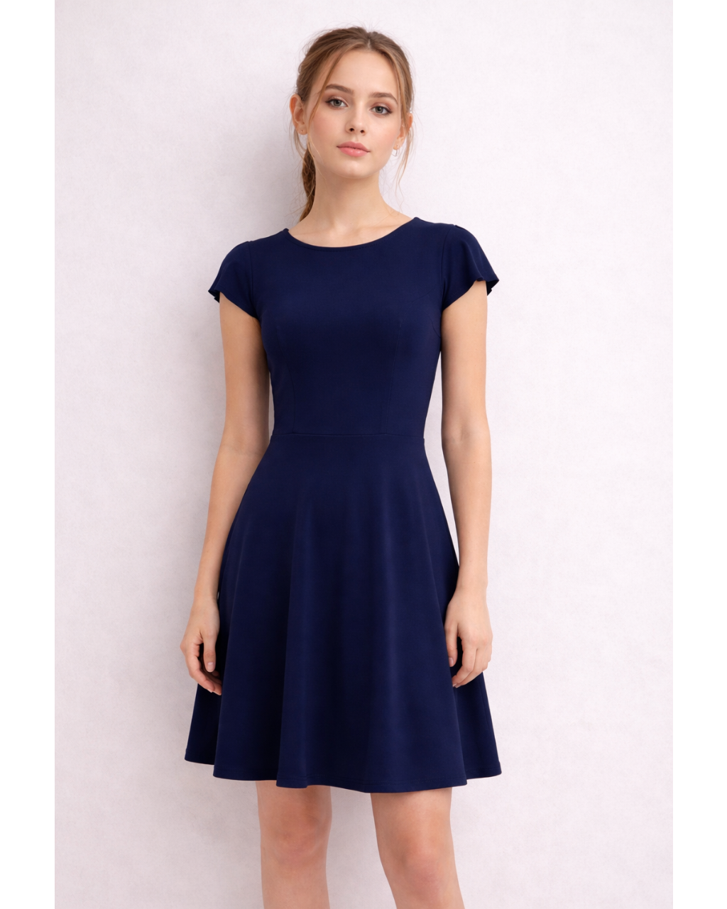 Woman wearing a navy blue dress against a light pink background