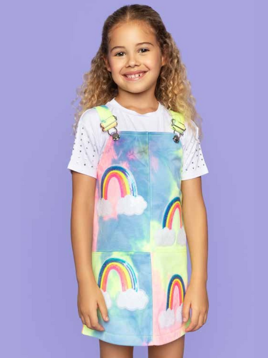 A girl wearing a rainbow overalls dress and a white t-shirt