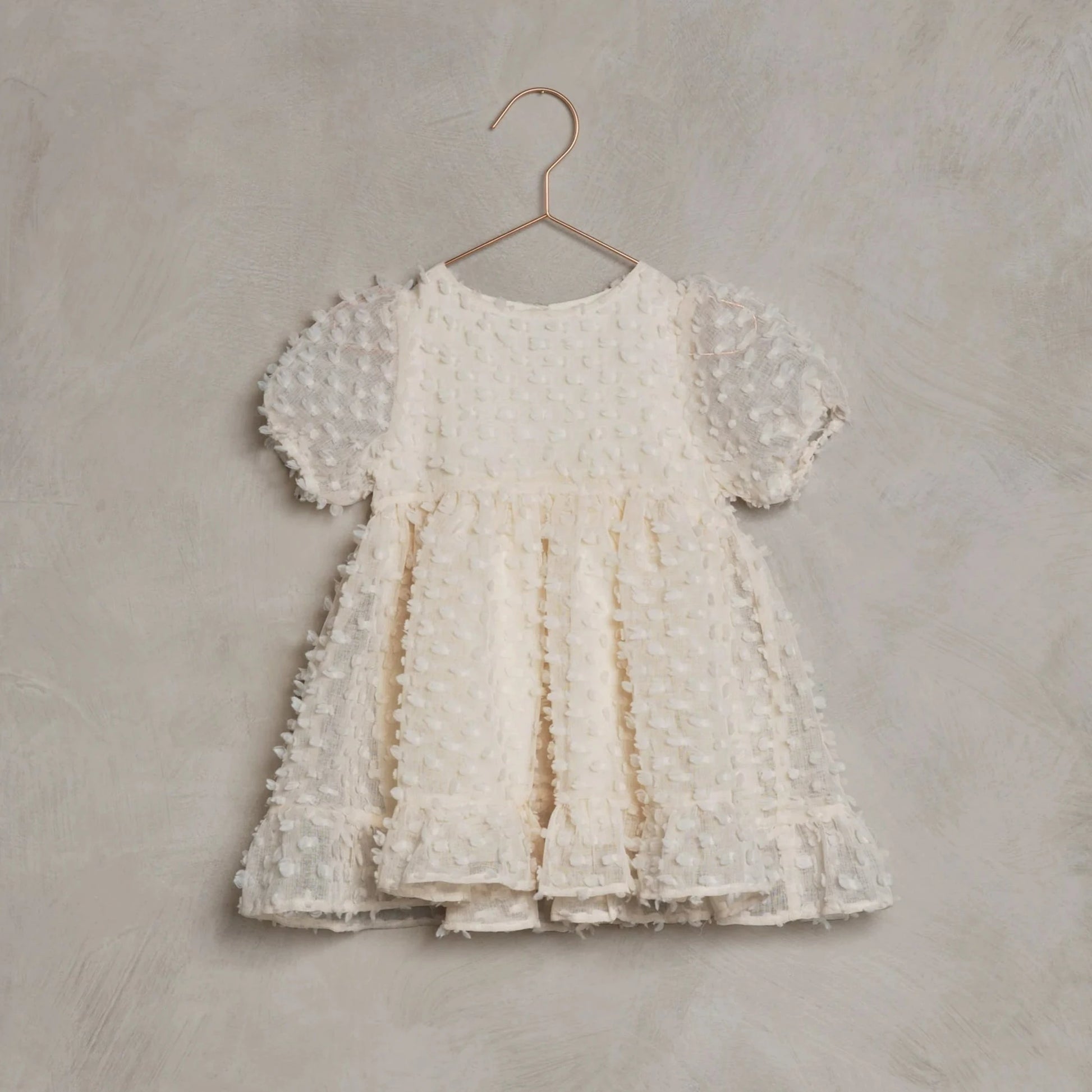 This adorable Noralee Quinn dress features pretty puff sleeves and a babydoll inspired silhouette. Scooped neck and button back closure.
